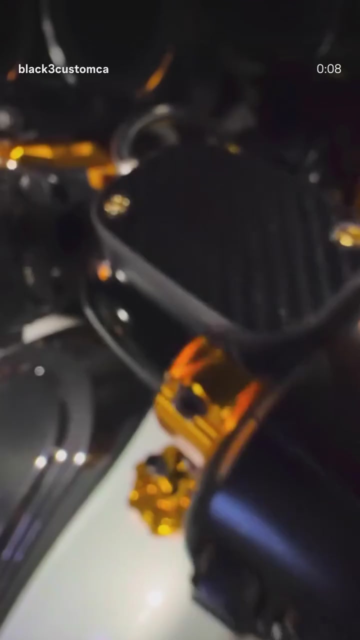 Custom Harley-Davidson with Black3 gold billet parts at a night show